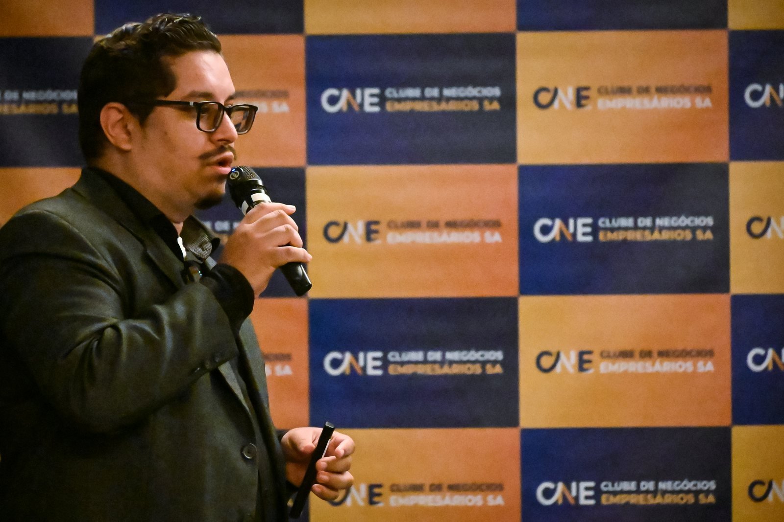 André Santana falando ao microfone em palestra no Clube de Negócios Empresários, o CNE