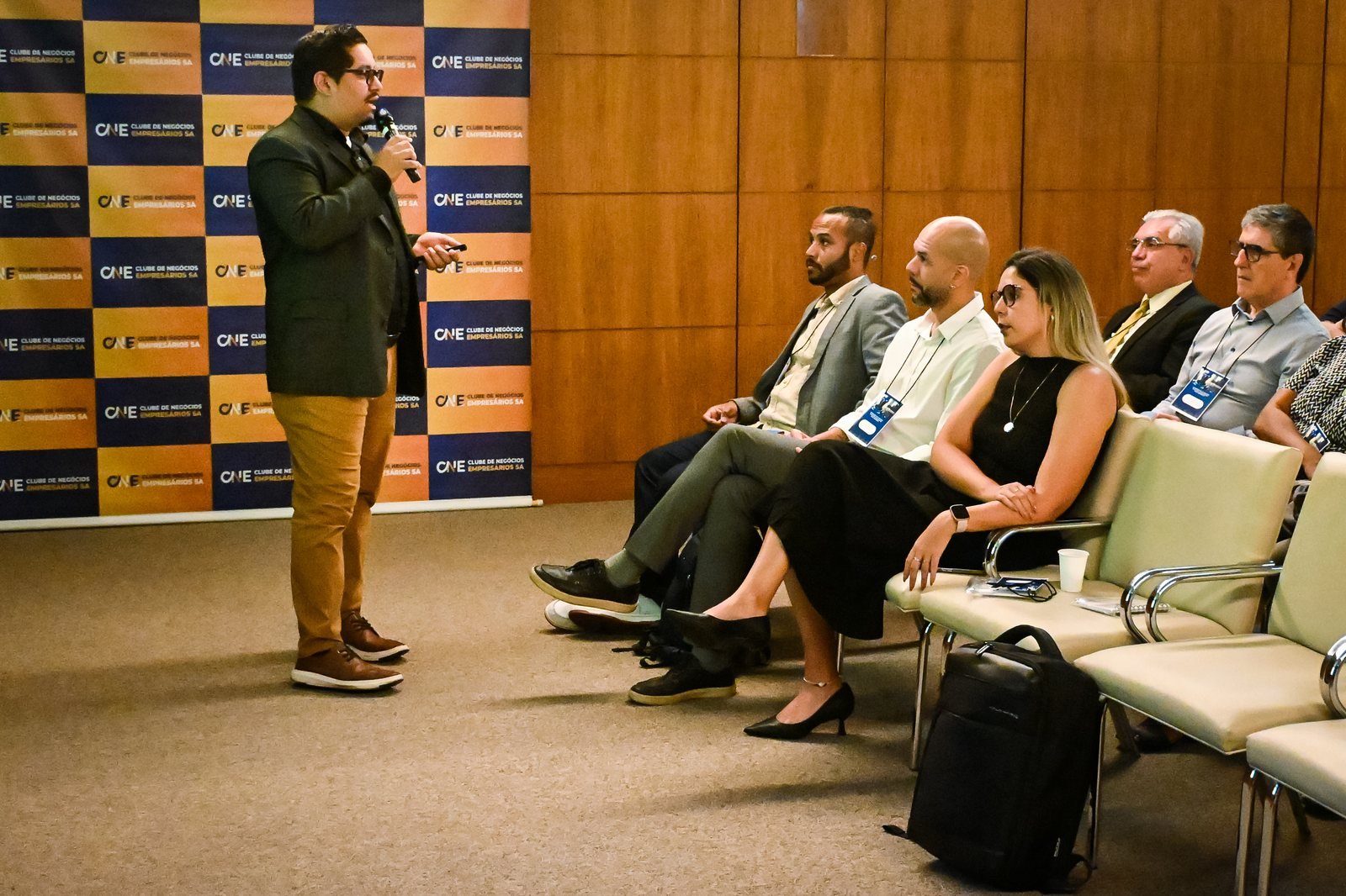 André Santana palestrando para uma plateia sentada no evento do Clube de Negócios Empresários